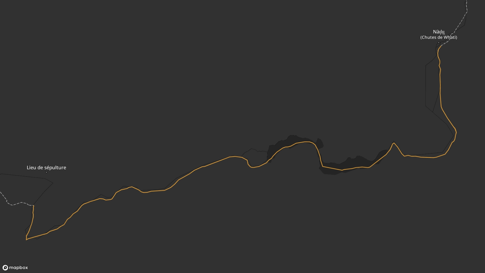 Vue cartographique de l'itinéraire de la piste de Whatì depuis Nàı̨lı̨ı̨ (chutes de Whatì) au nord-est, jusqu'à une tombe inconnue le long de la rivière au sud-ouest. La rivière traverse le paysage en zigzaguant. 