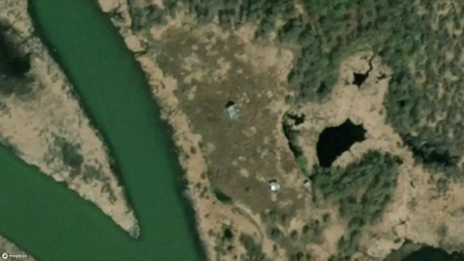 Vue satellite des deux rivières qui se séparent à Dètaè?aa. Les toits de deux petites cabanes sont visibles dans la clairière, juste au bord de la rivière.